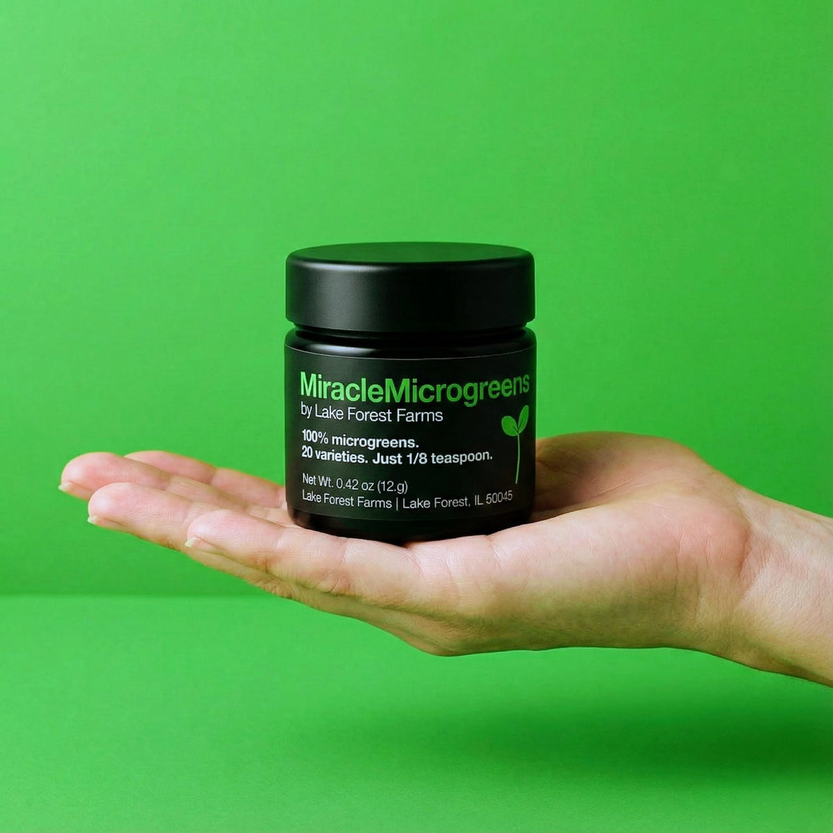 Hand holding a jar of MiracleMicrogreens